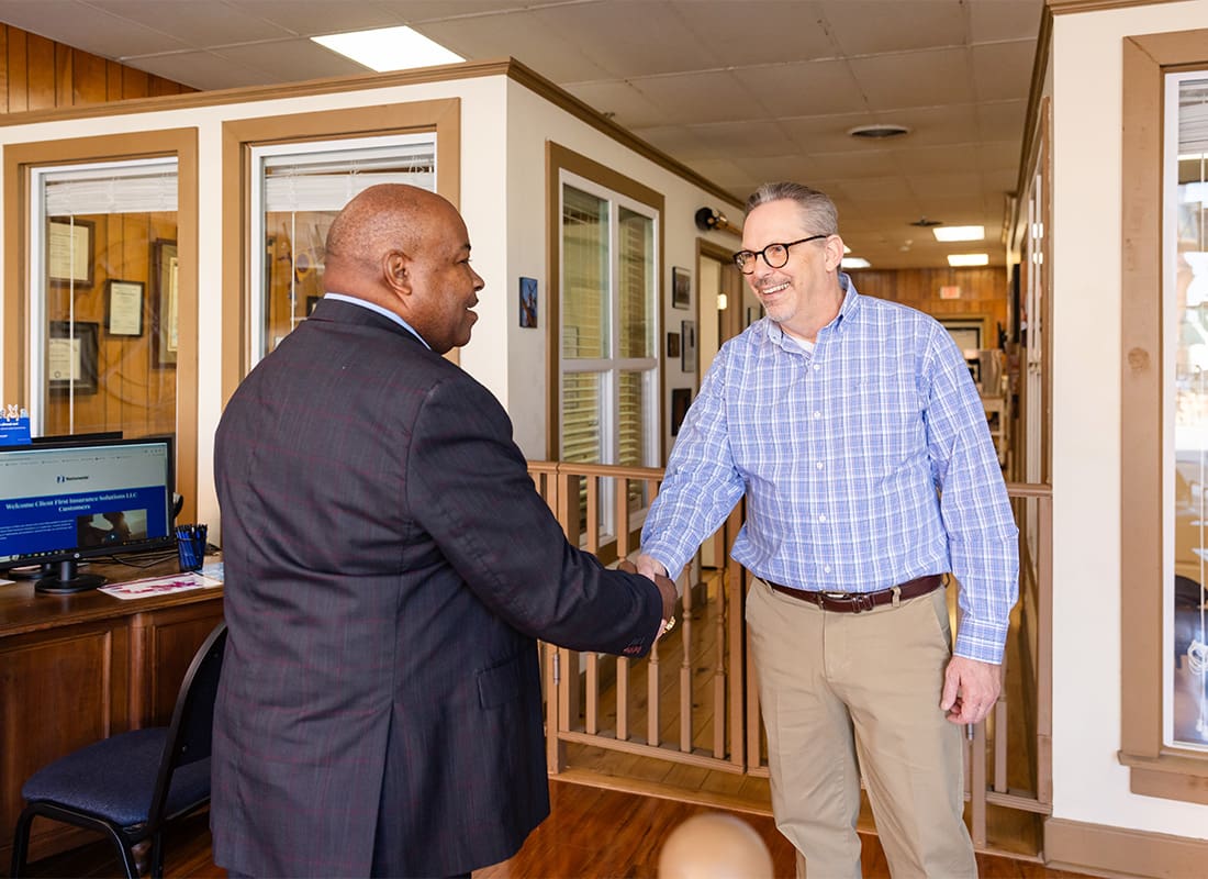 Service Center - Portrait of Kirk from Client First Insurance Solutions Shaking Hands with a Businessman Inside the Office