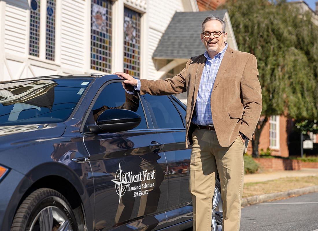 We Are Independent - Kirk from Client First Insurance Solutions Standing Next to the Company Car Outside on a Sunny Day